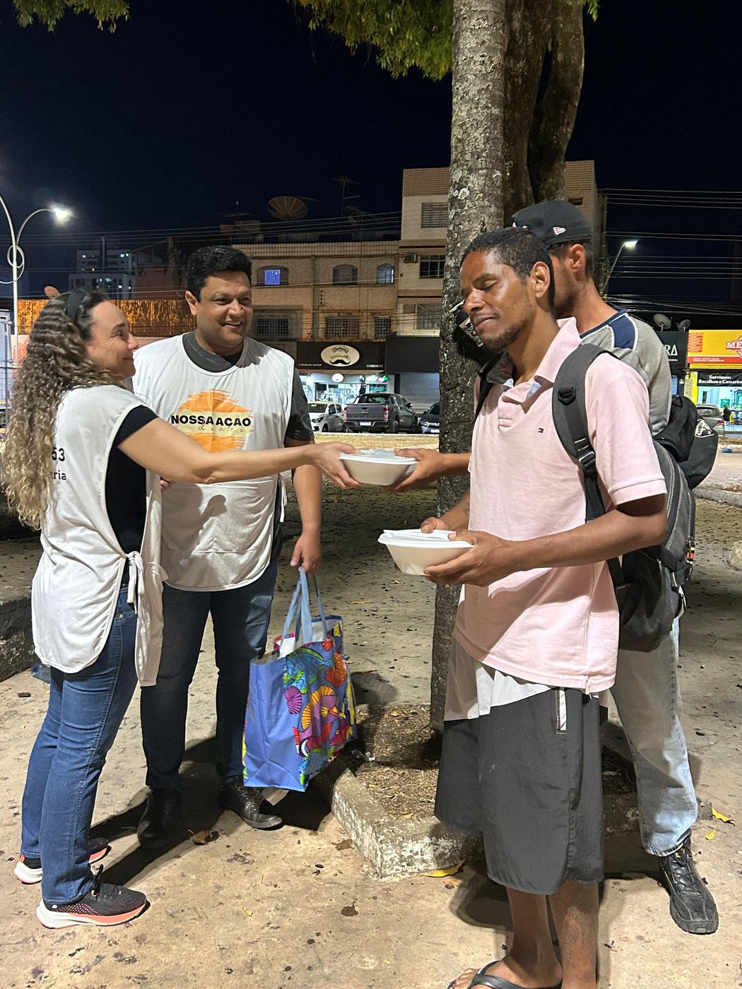 Voluntários entregando marmita para um jovem na rua