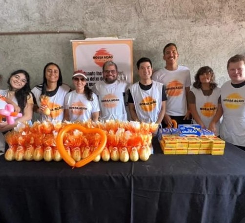Equipe de voluntários de colete da Nossa Ação, mesa pronta para a festa